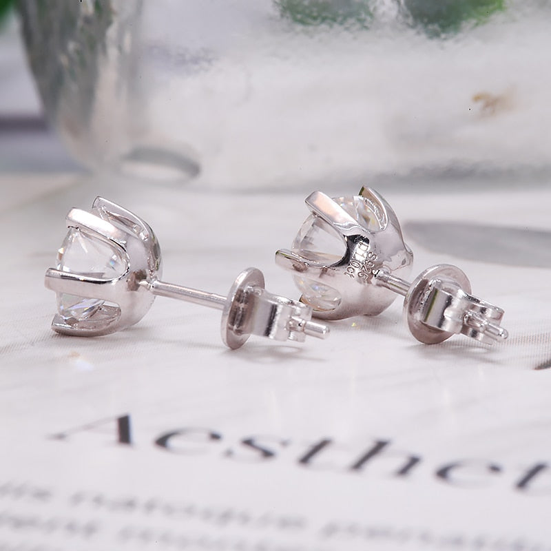 A silver round pair of stud earrings with clear stones.