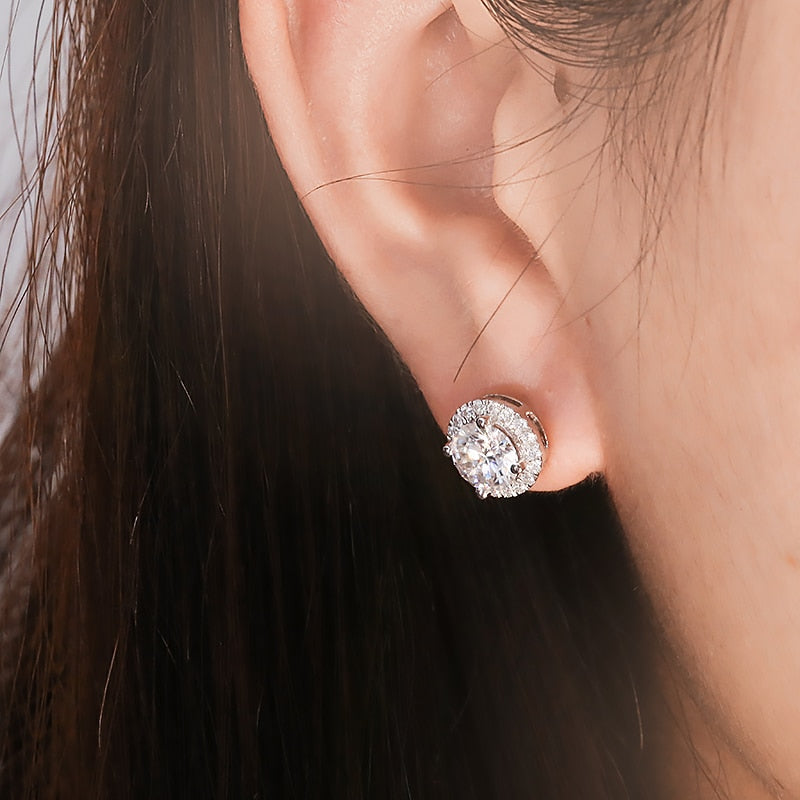 A person wearing a silver moissanite halo earring stud.