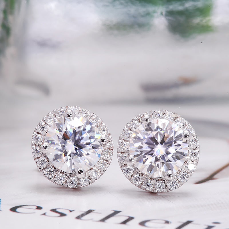 A silver pair of moissanite halo earring studs.