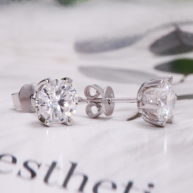 A silver round pair of stud earrings with clear stones.