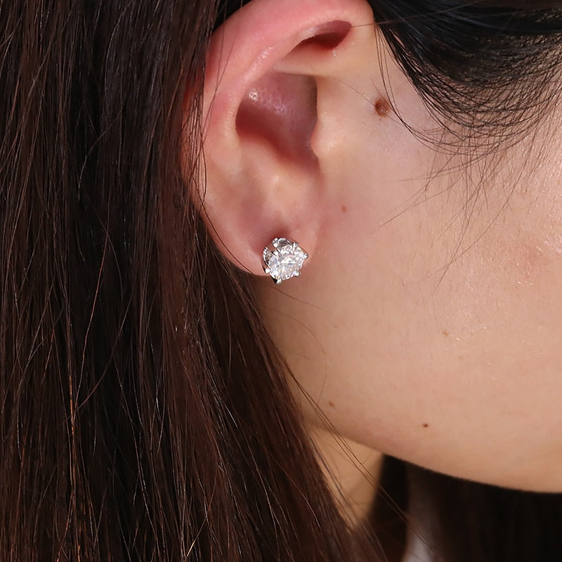 A woman wearing a silver round stud earring with a clear stone.