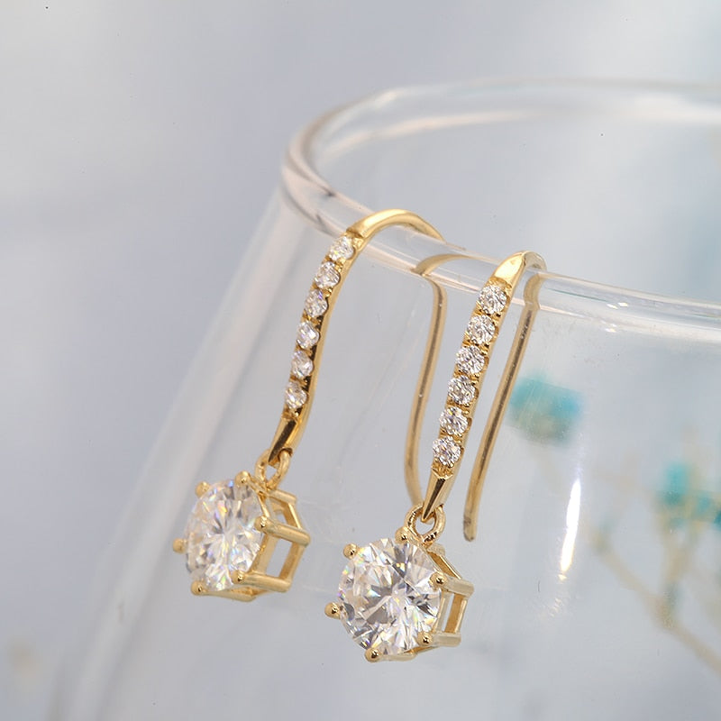 A gold pair of dangling earrings set with round clear stones.