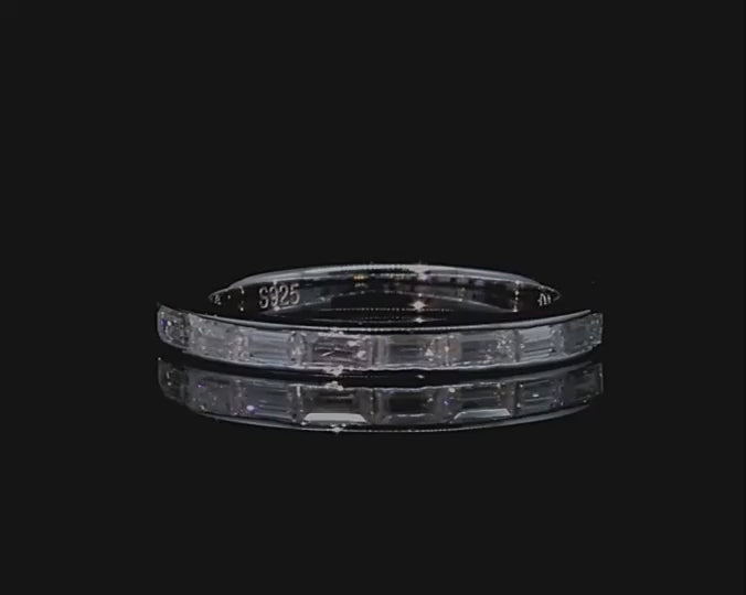 A silver wedding ring channel set with 9 baguettes horizontally and spinning on a viewing platform.