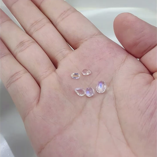 5 various cut moonstones displayed in a hand.
