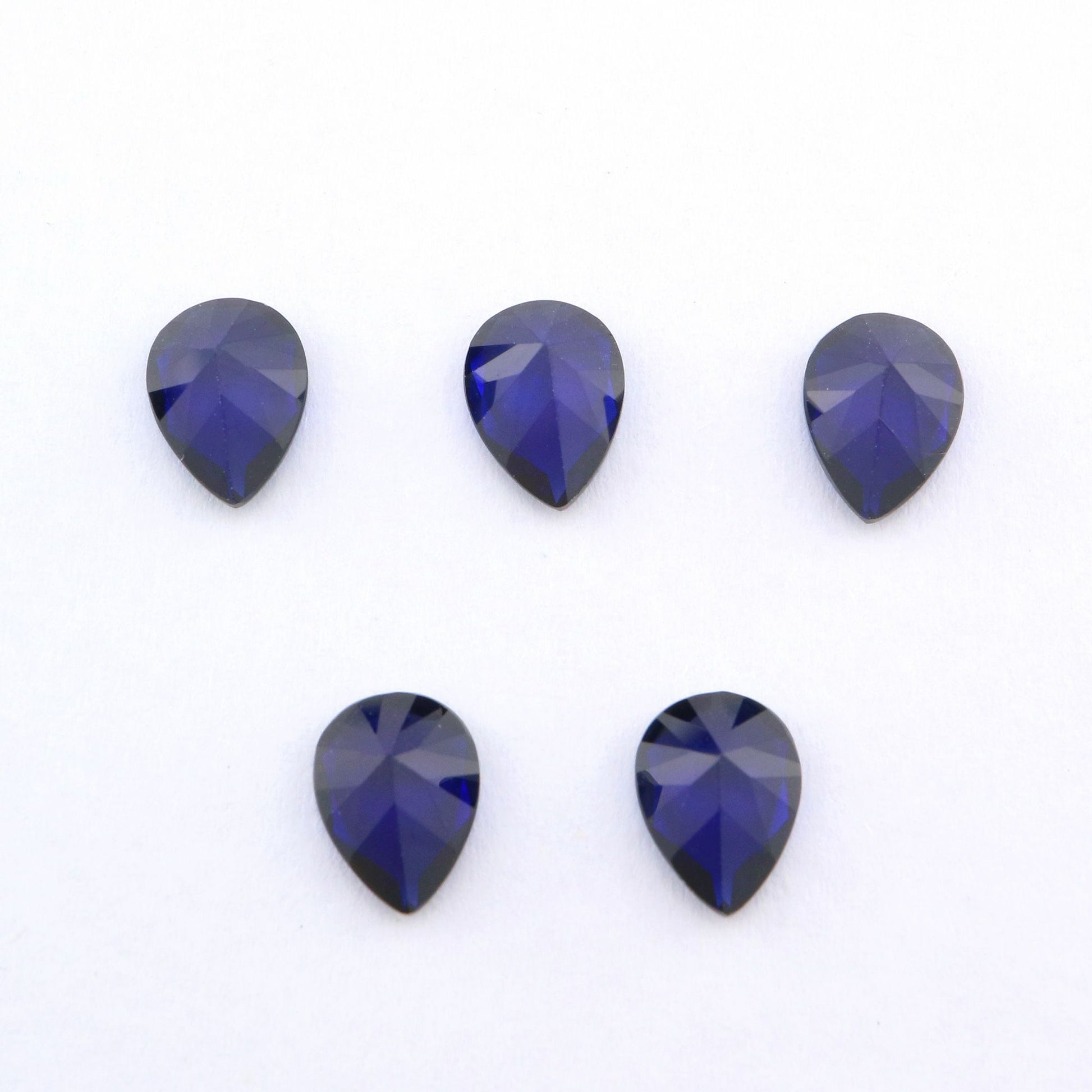 Five tear drop cut dark blue lab created sapphire.