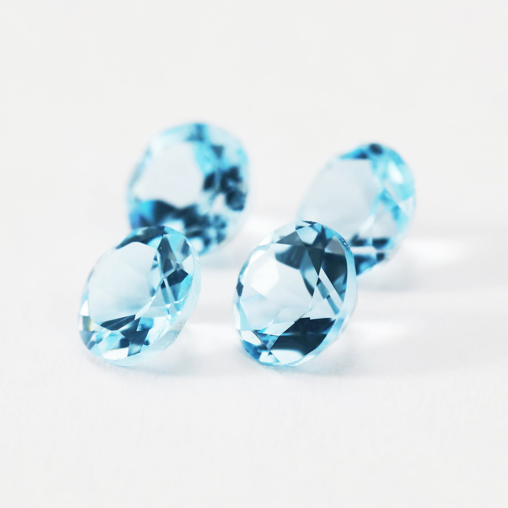 Four round blue sky blue topaz gems.