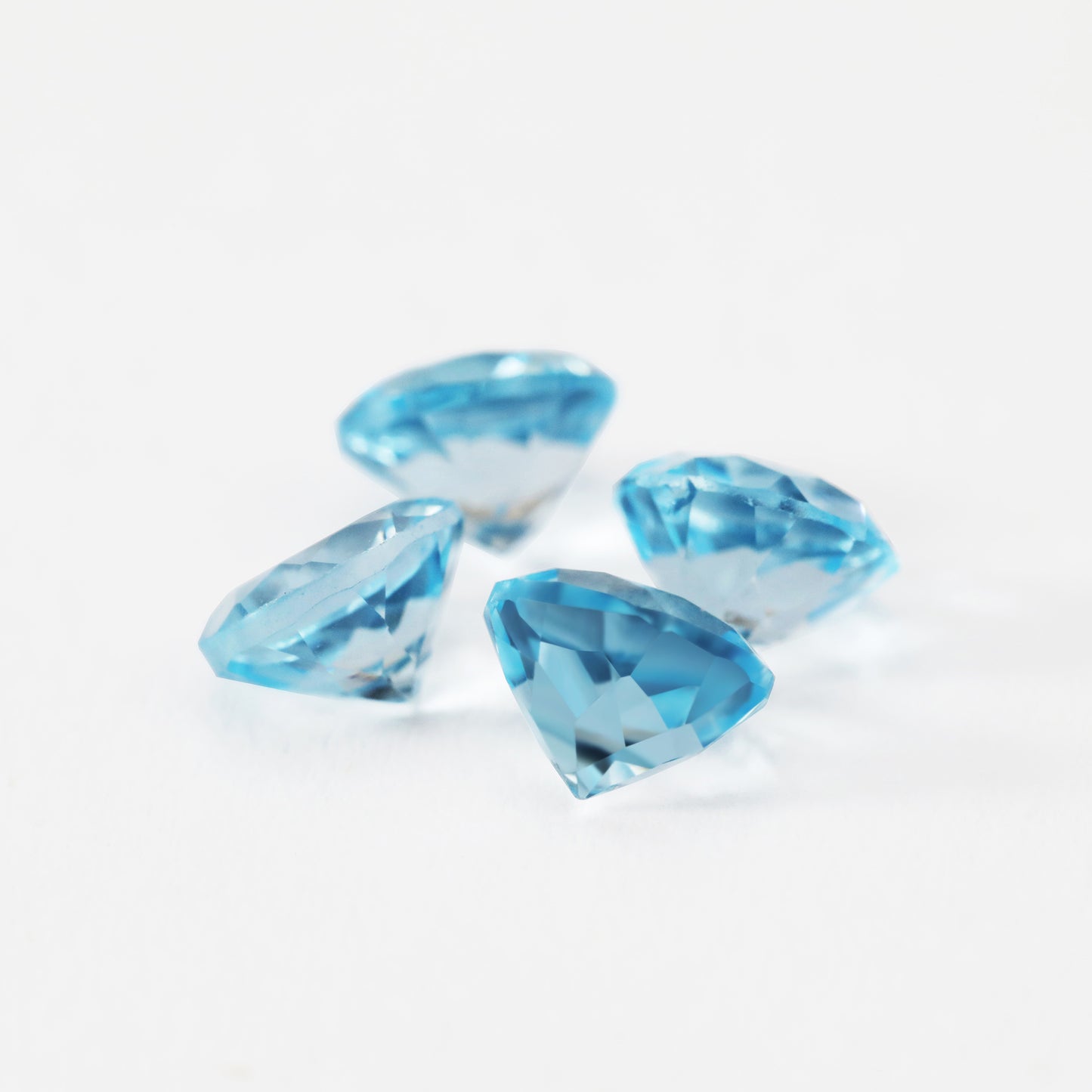 Four round blue sky blue topaz gems.