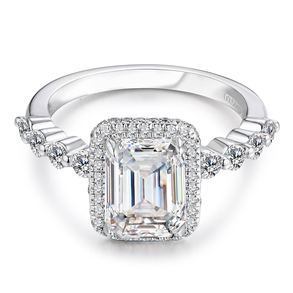 A silver vintage style scalloped shank emerald cut moissanite halo ring.