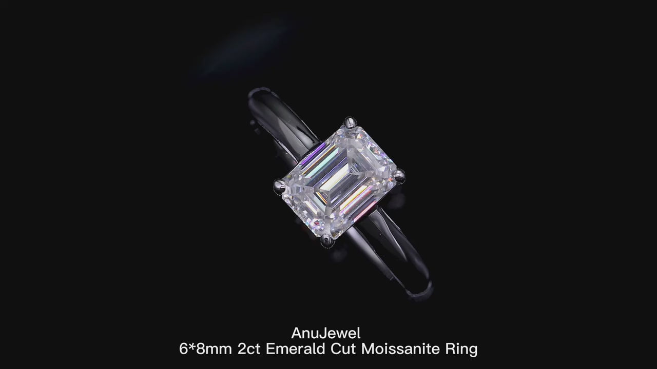 A Spinning sparkling 2CT emerald cut moissanite sterling silver ring on a display.