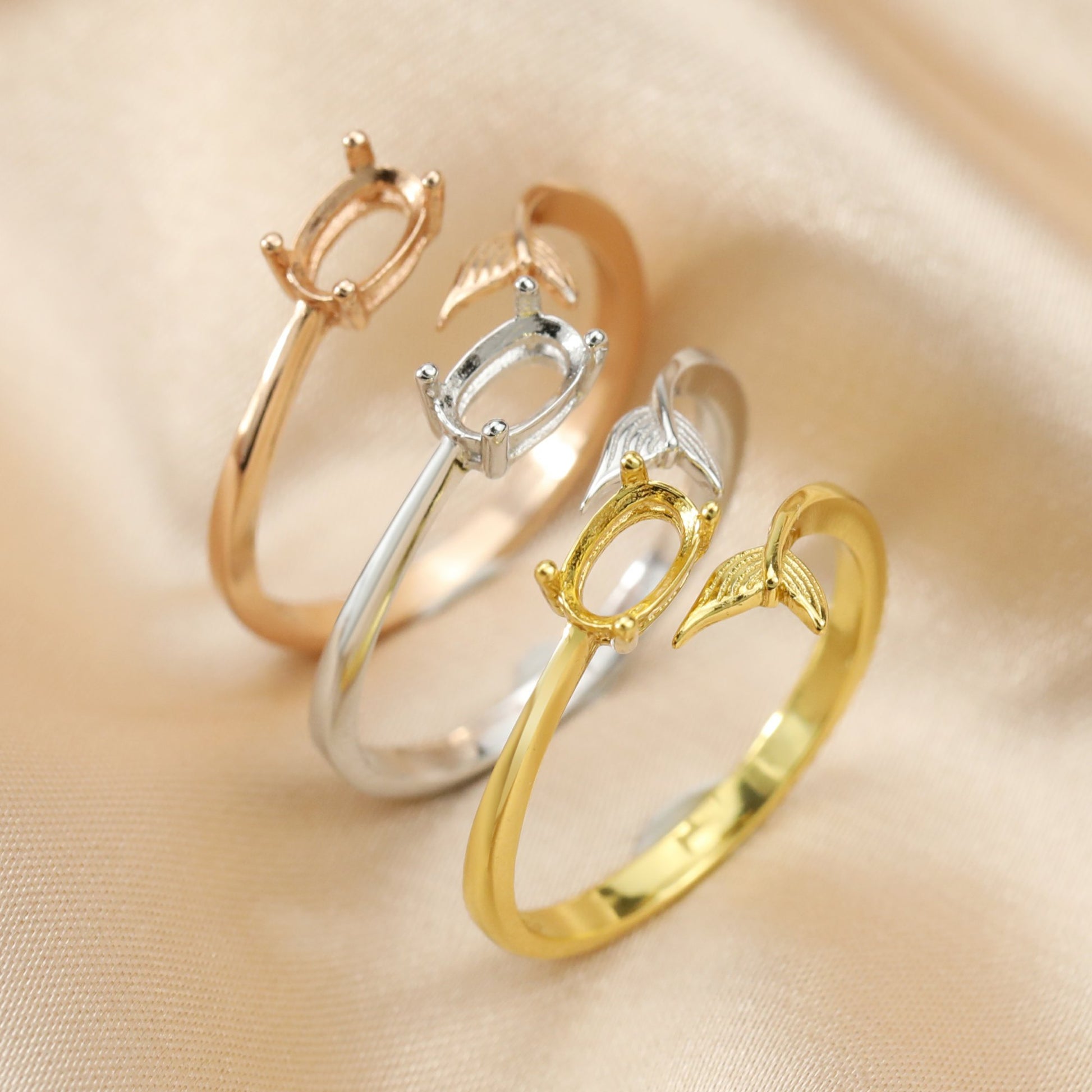 One silver, one gold and one rose gold oval wrap around rings with a mermaid tail on the opposite ends.