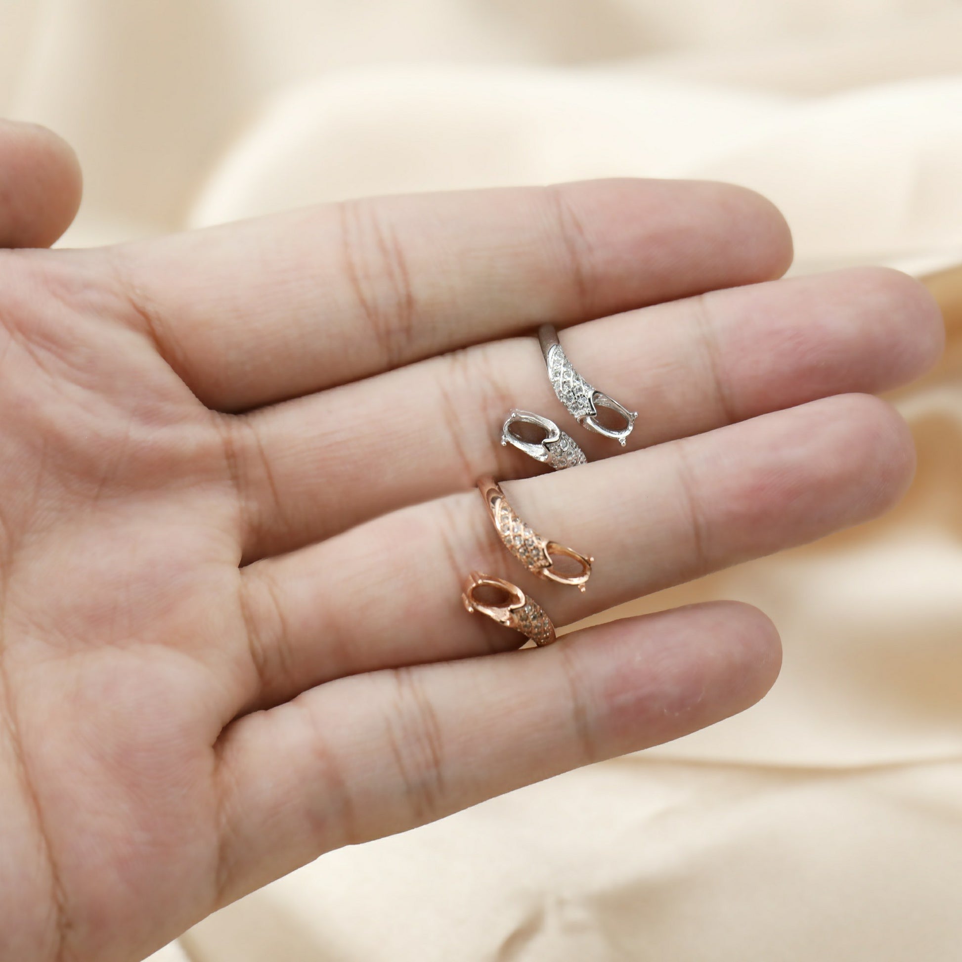 A hand wearing one silver and one rose gold oval scale wrap around bypass semi mount