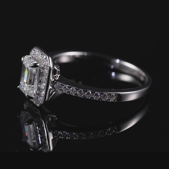 A silver emerald cut halo ring spinning and sparkling on a viewing platform.