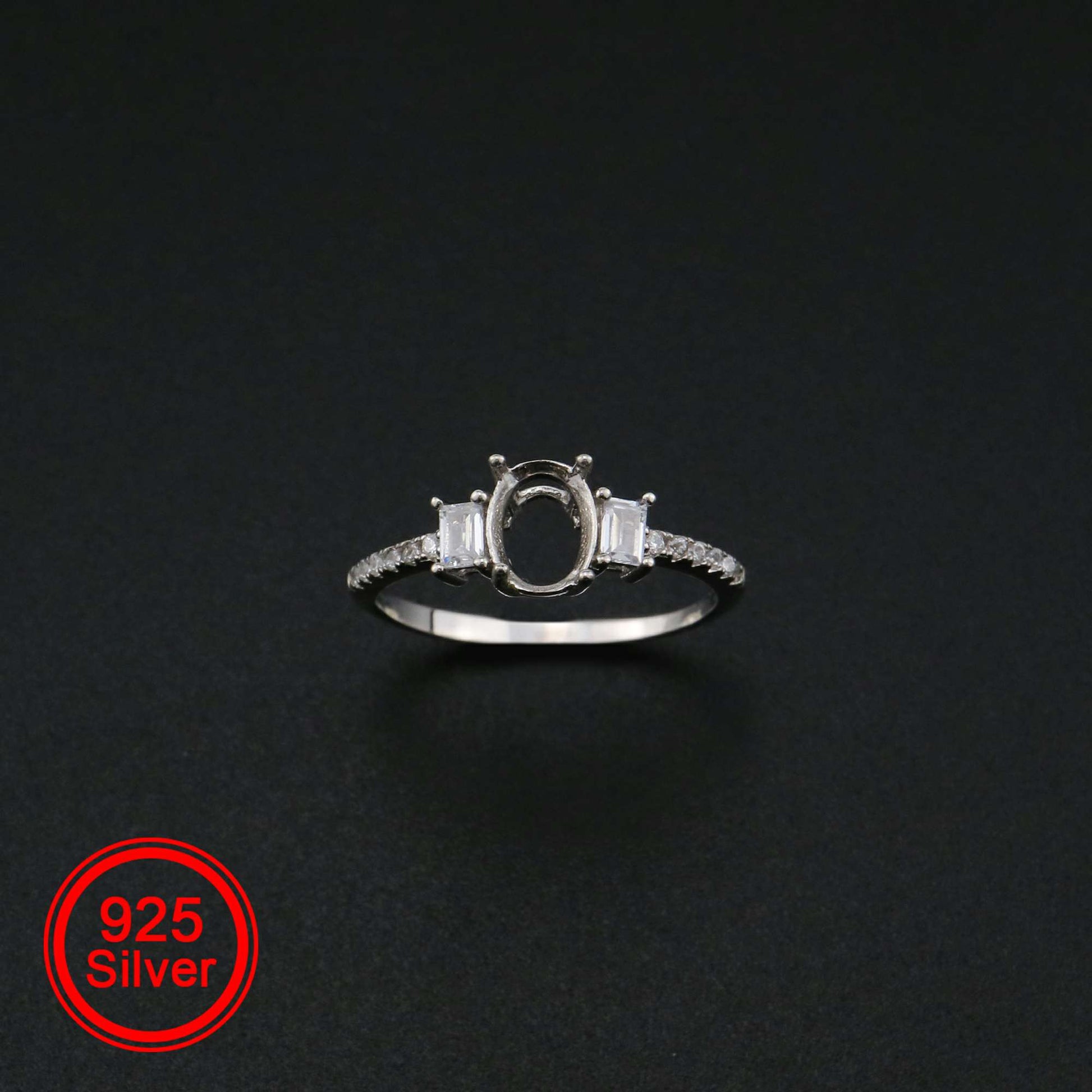 A silver oval shaped 3 stone semi mount with emerald cut gems on the sides.
