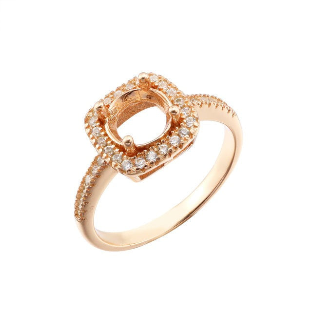 A rose gold semi mount for a round gem with a slightly squared halo.