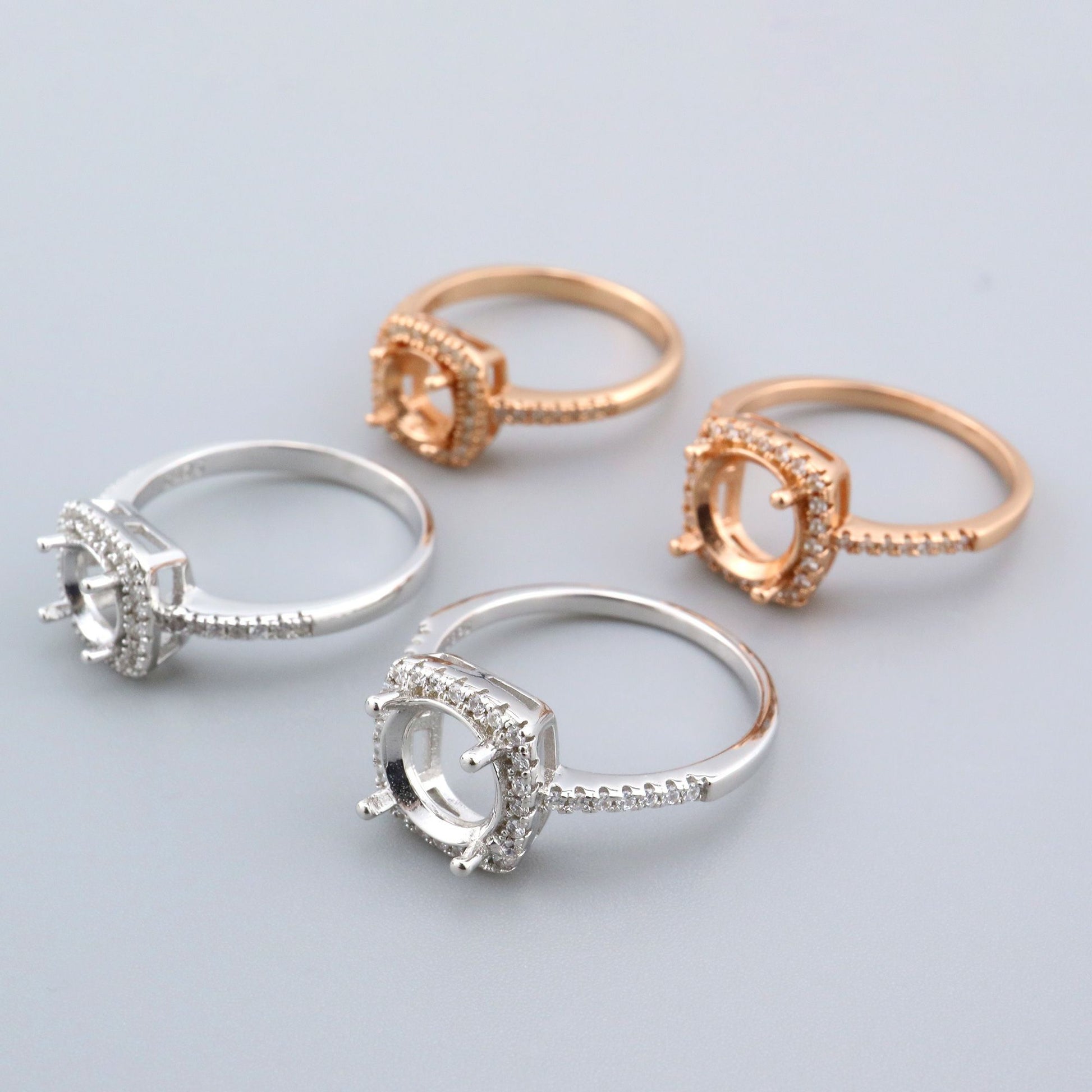 2 silver and 2 rose gold semi mounts for a round gem with a slightly squared halo.