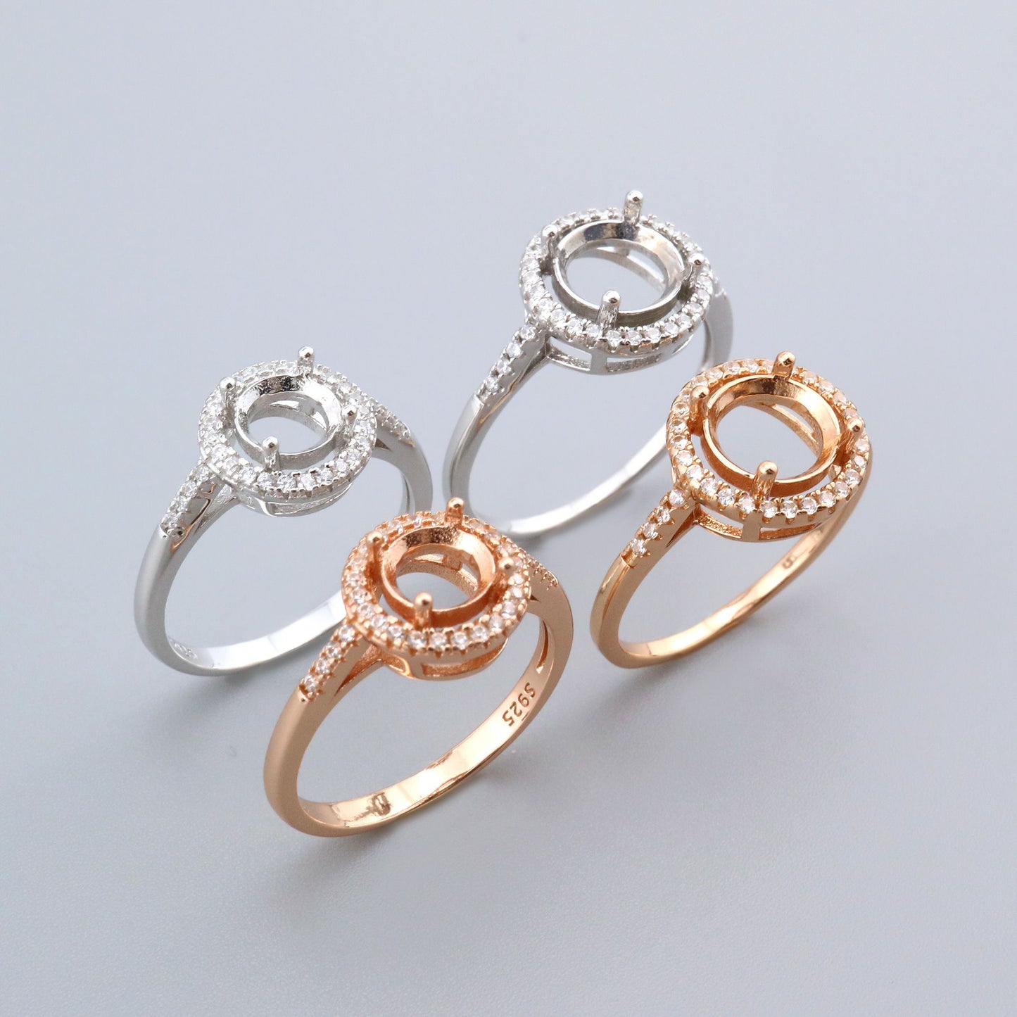 Two silver and two rose gold round halo semi mounts.