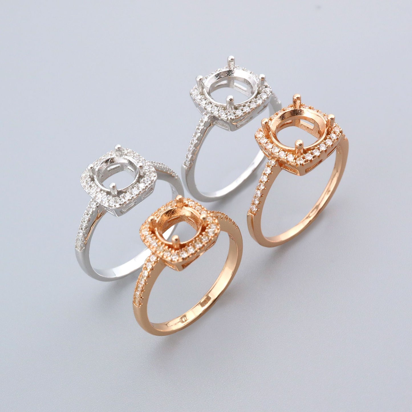 2 silver and 2 rose gold semi mounts for a round gem with a slightly squared halo.