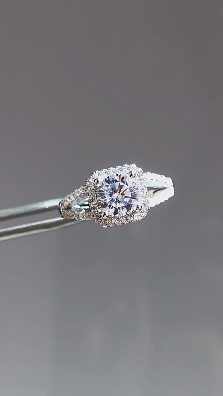 Silver pave split shank squared halo set with a round moissanite being displayed.