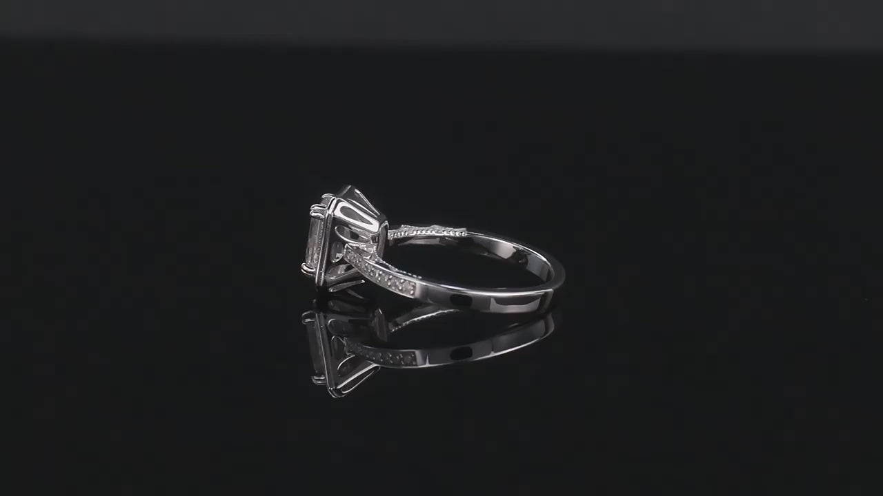 A silver halo ring set with an emerald cut moissanite spinning on a viewing platform.