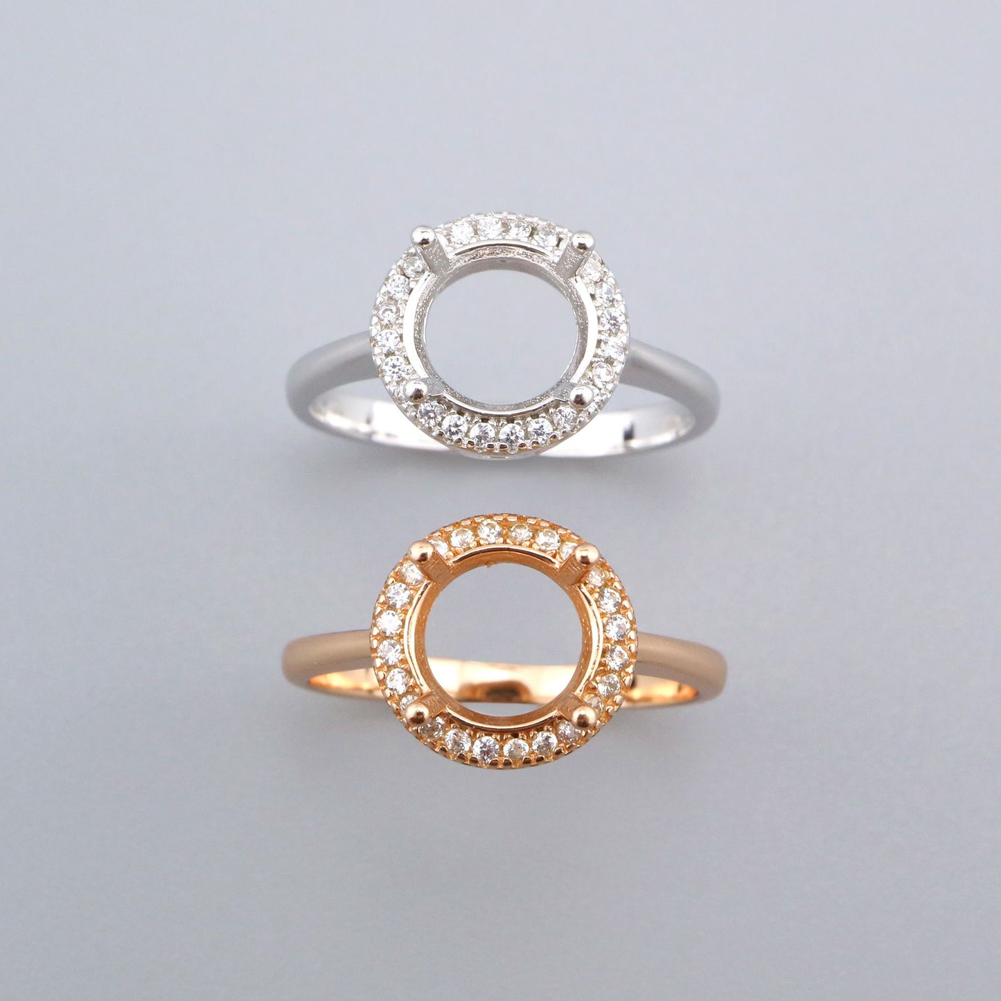 One silver and one rose gold round halo semi mounts with filigree cutouts.