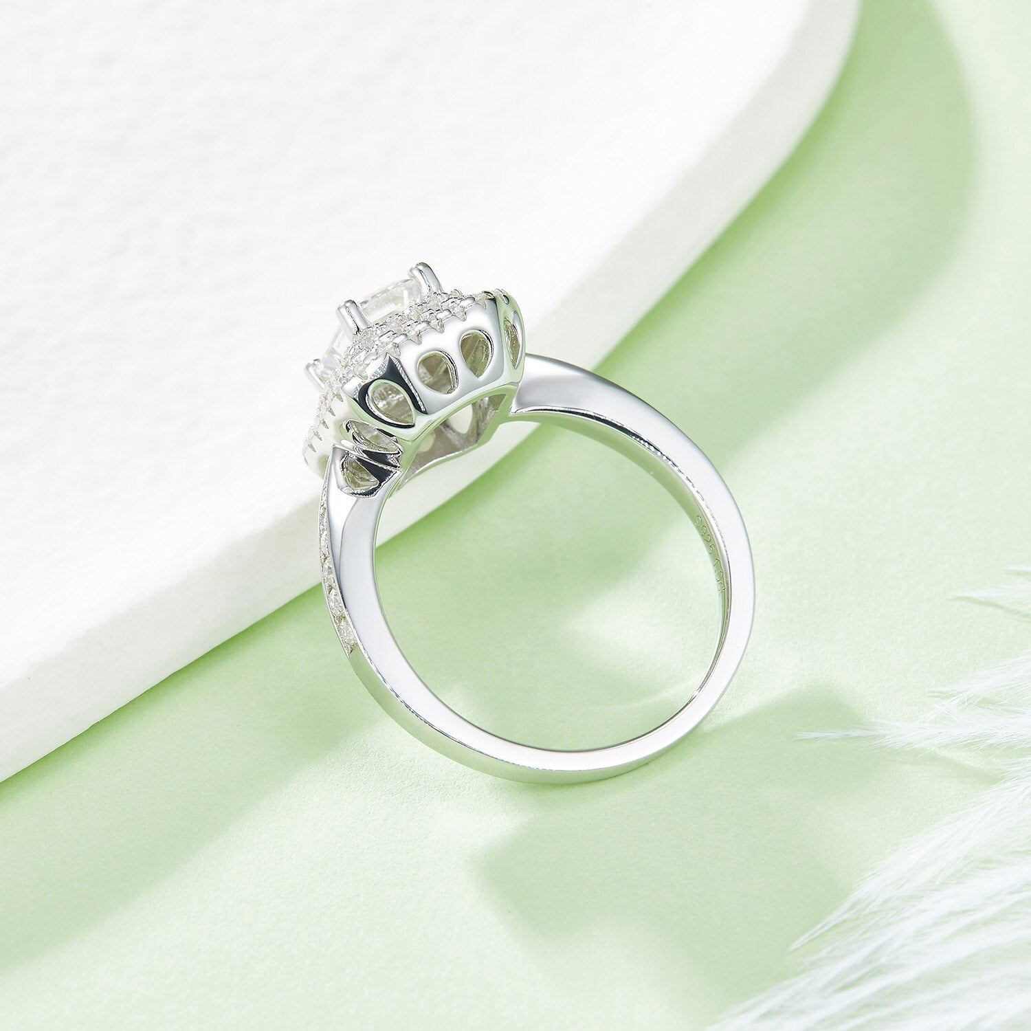 A silver ring set with an emerald cut moissanite in a double halo with a tapered gem encrusted band.