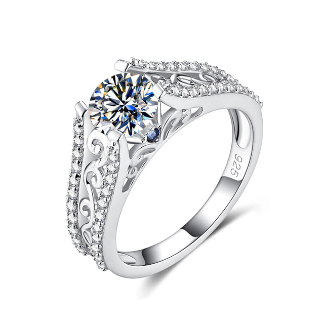 A filigree silver moissanite engagement ring with a small blue sapphire set on each side.