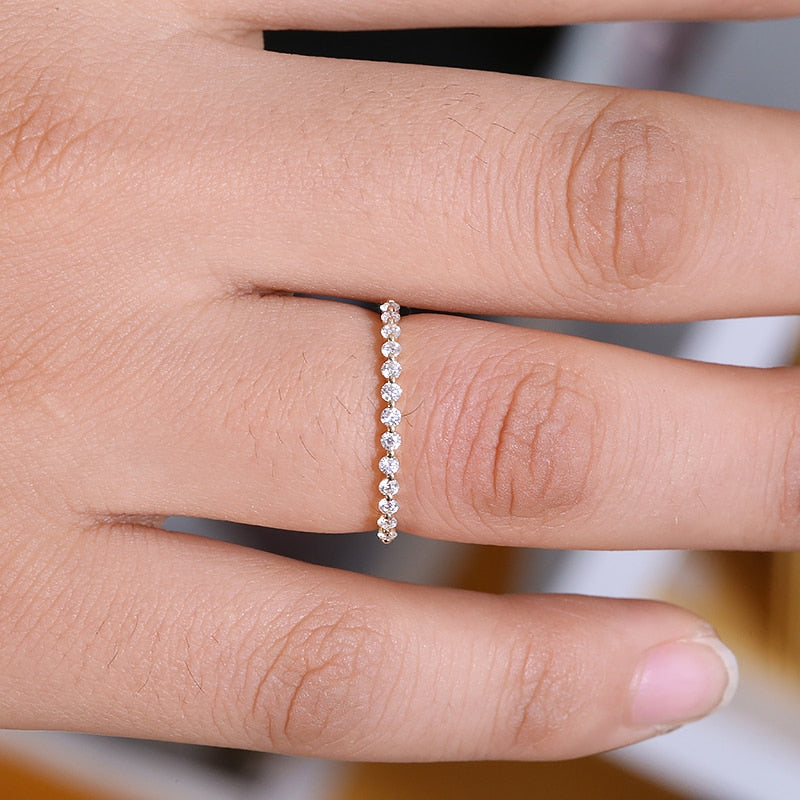 A hand wearing a gold bubble band wedding ring with sparkling moissanite gems.