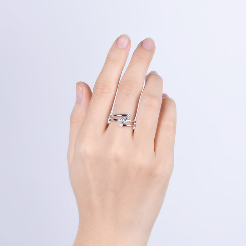 A hand wearing a silver spiral bypass 3 stone ring.