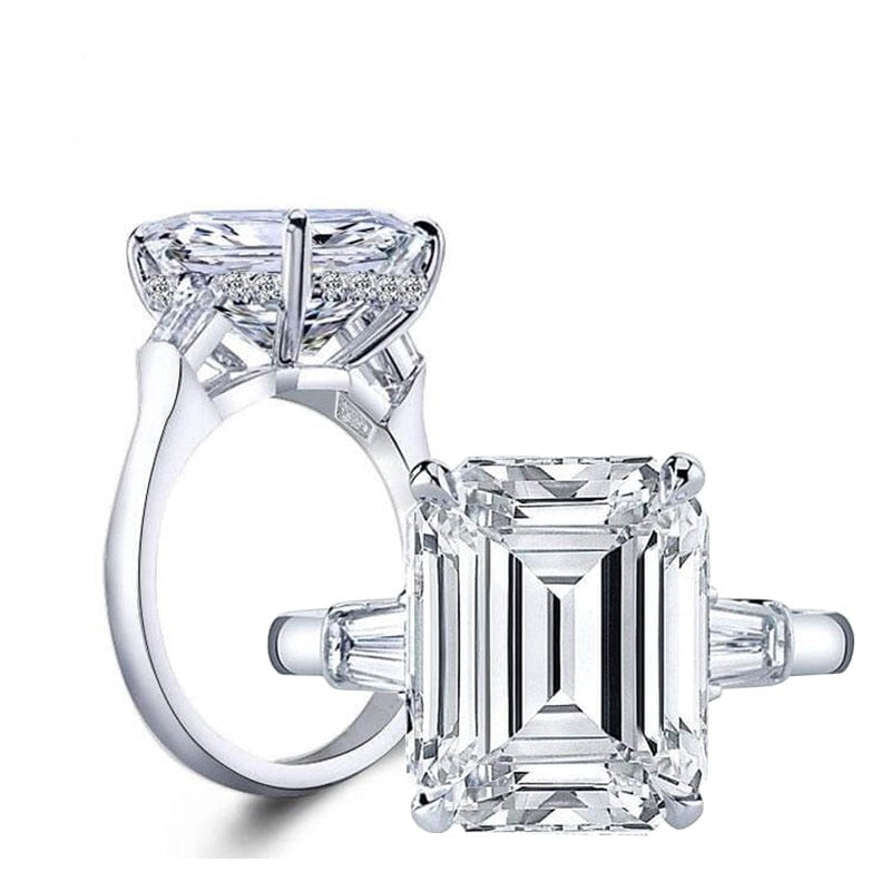 Two silver large emerald cut moissanite rings.