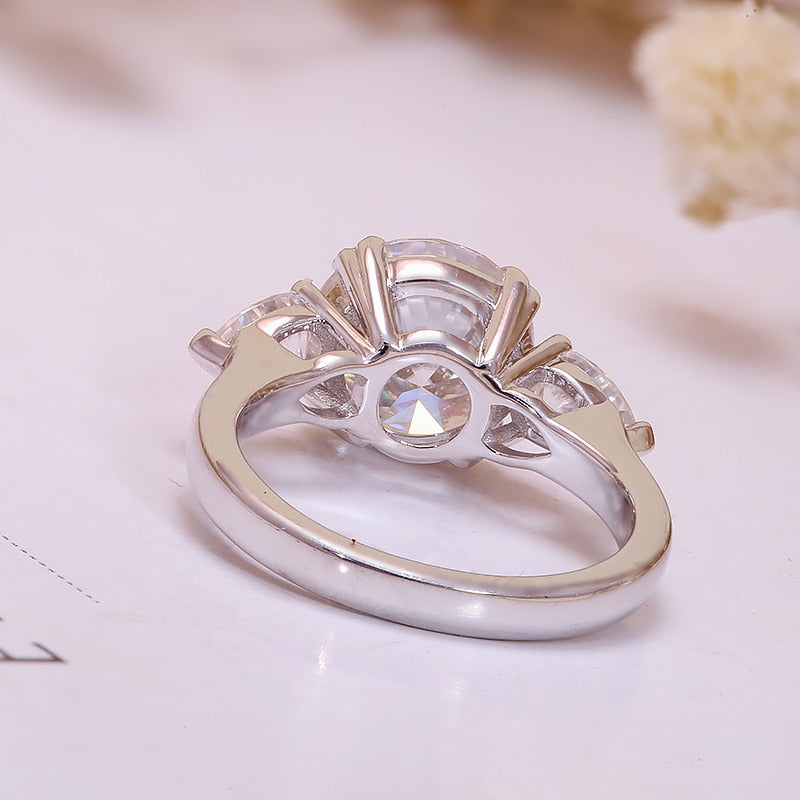 A silver 3 stone ring set with a 3.5CT round moissanite set between two 0.5CT tear drop moissanites.