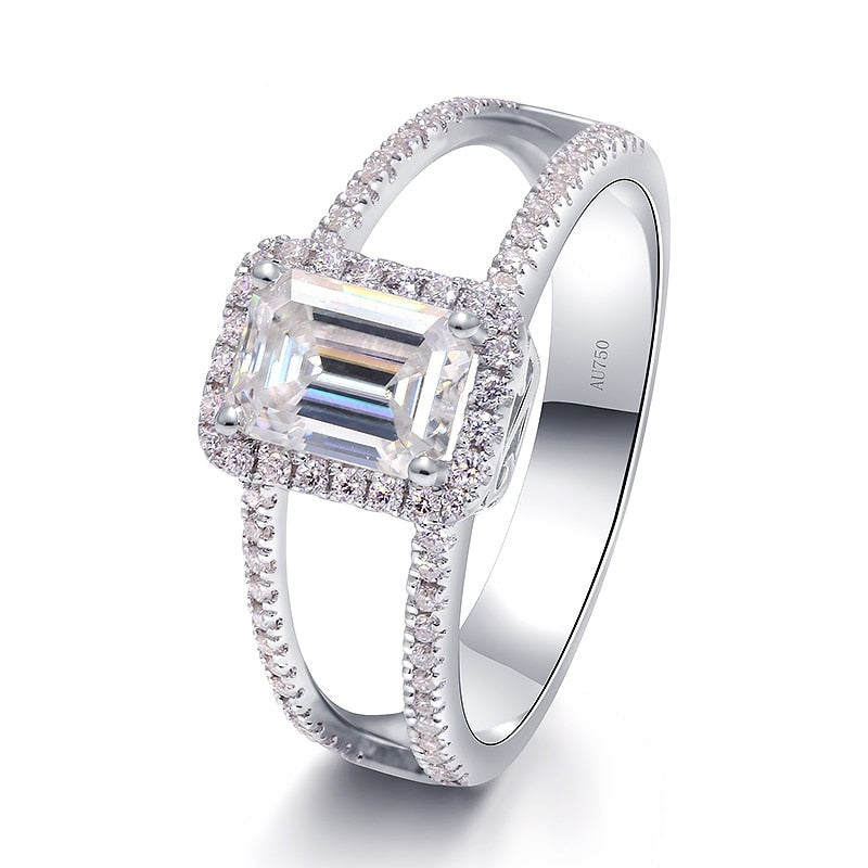 A silver ring set with a emerald cut moissanite with a wide split pave band.