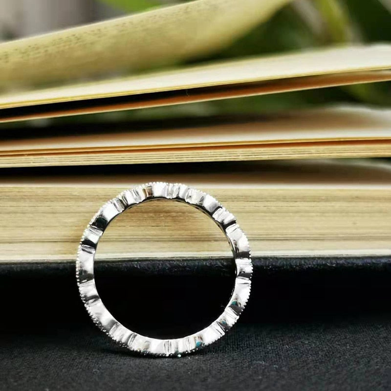 A silver scalloped art deco wedding band with small moissanites varying from 1 to 2 gems all the way around the eternity band.