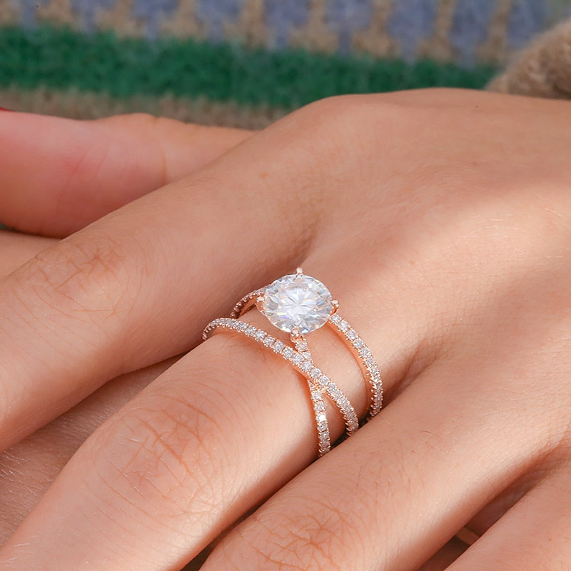 A hand wearing a rose gold pave triple banded ring set with  round moissanite in the center.