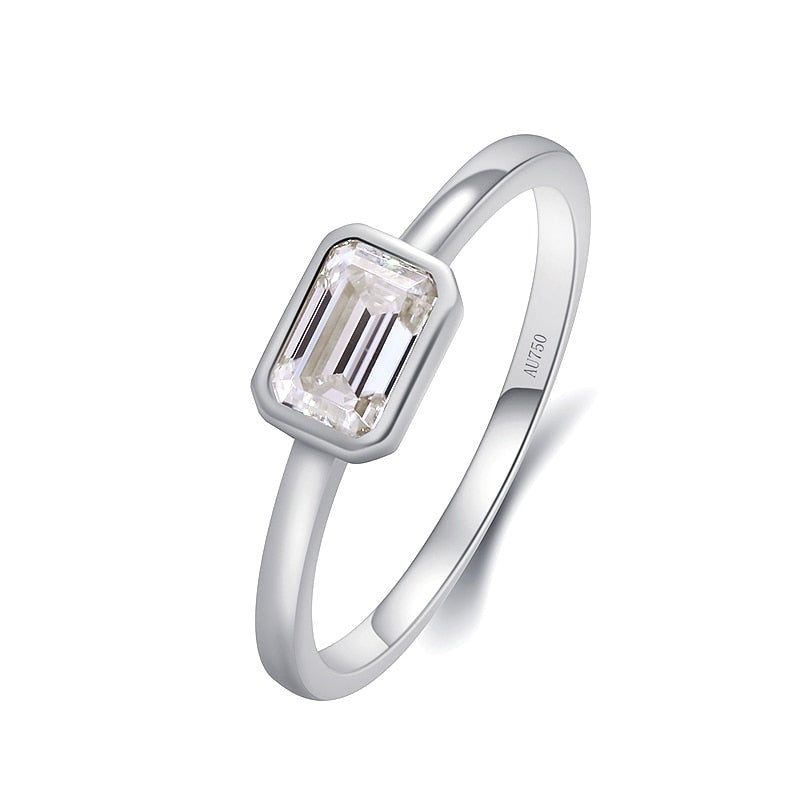A silver ring that has a emerald cut moissanite bezel set east to west.