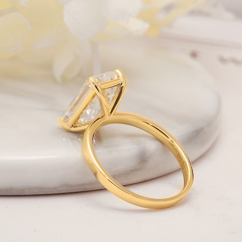 A gold solitaire ring basket set with a 4CT emerald cut moissanite.