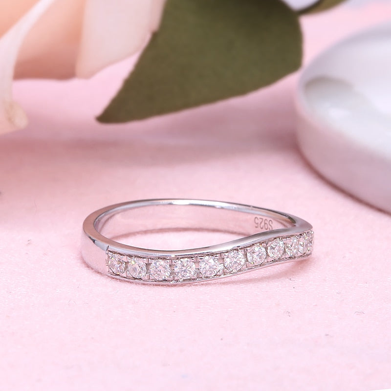 A silver curved wedding band with moissanites along the band.