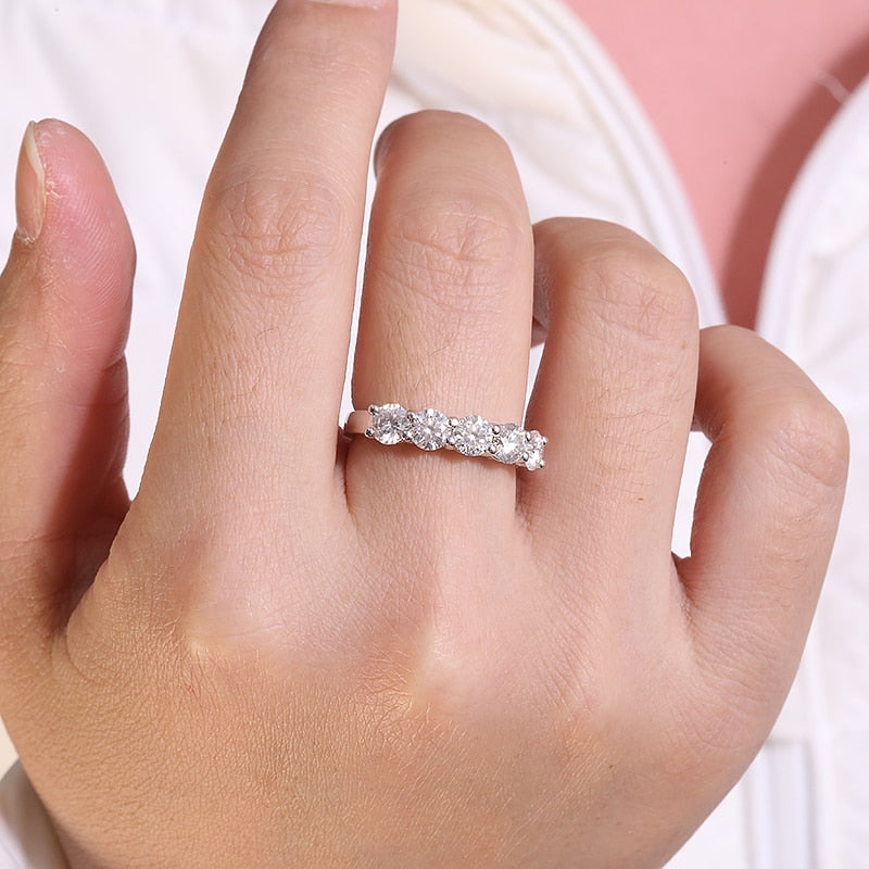 A hand wearing a silver 5 gem wedding ring.