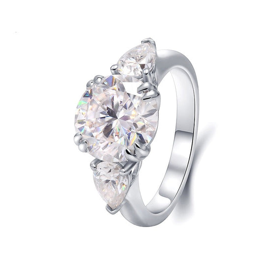 A silver 3 stone ring set with a 3.5CT round moissanite set between two 0.5CT tear drop moissanites.