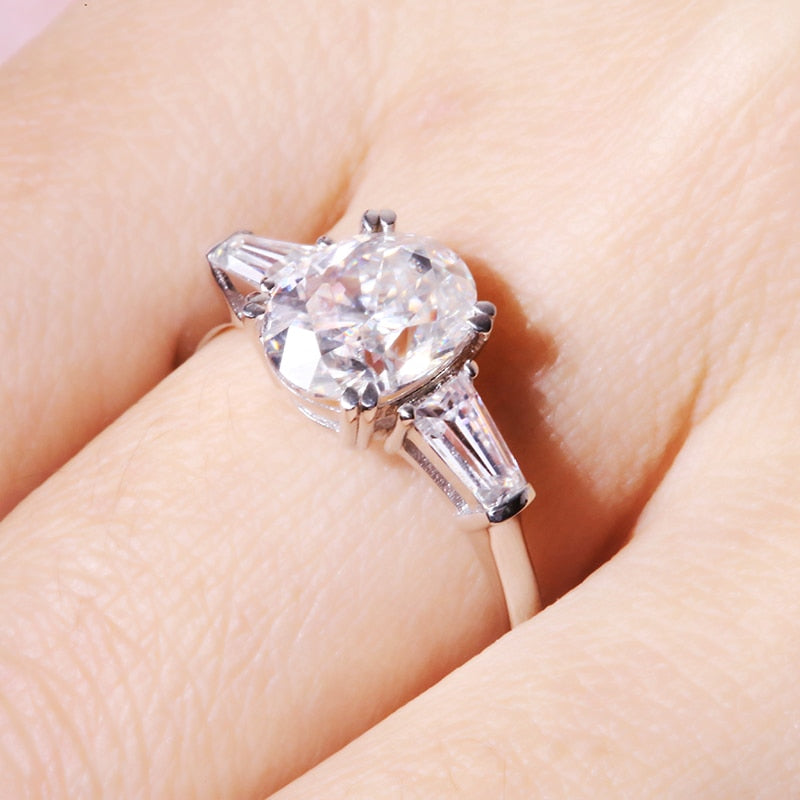 Solid white gold oval cut moissanite 3 stone engagement ring with accent baguettes on each side.