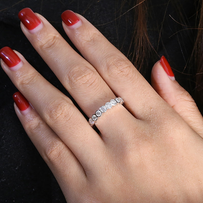 A hand wearing a tension set round cut moissanite eternity wedding ring.