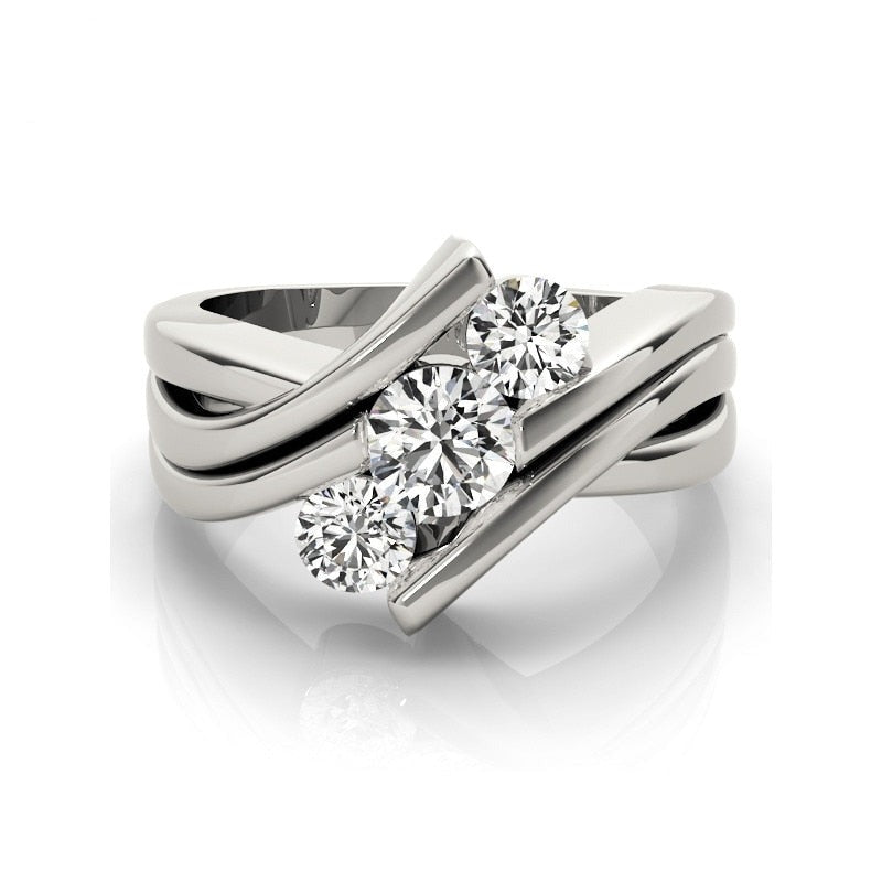 A silver 3 stone rings with moissanites tension set vertically at a diagonal angle between a triple bypass band.