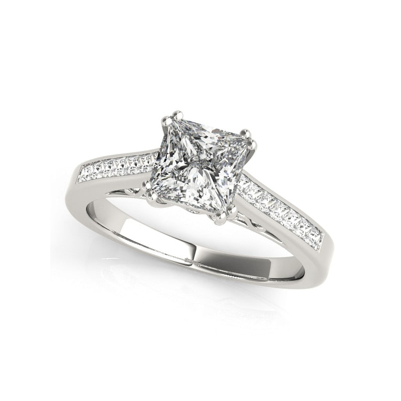 A silver engagement ring with a princess cut gem set on a filigree neck and channel set shank.