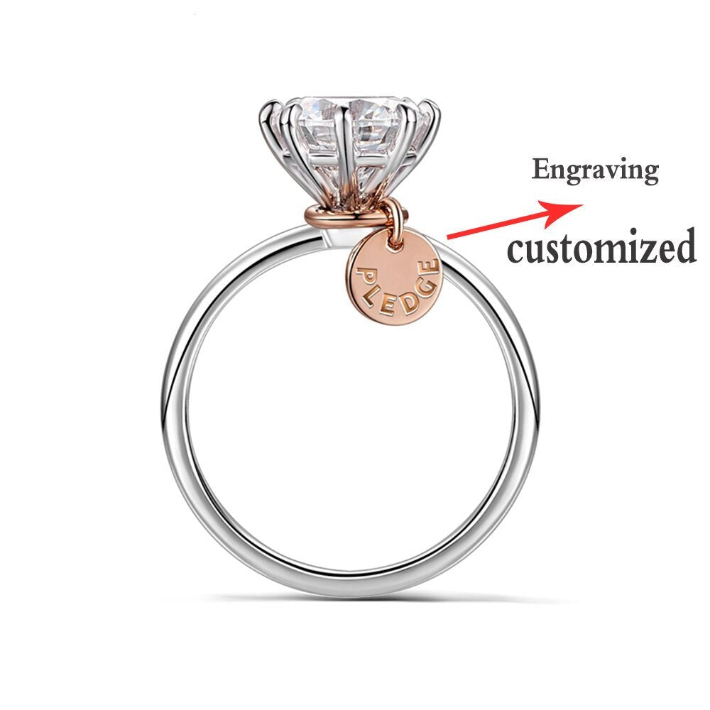 A silver round solitaire ring with a personalized rose gold name tag.