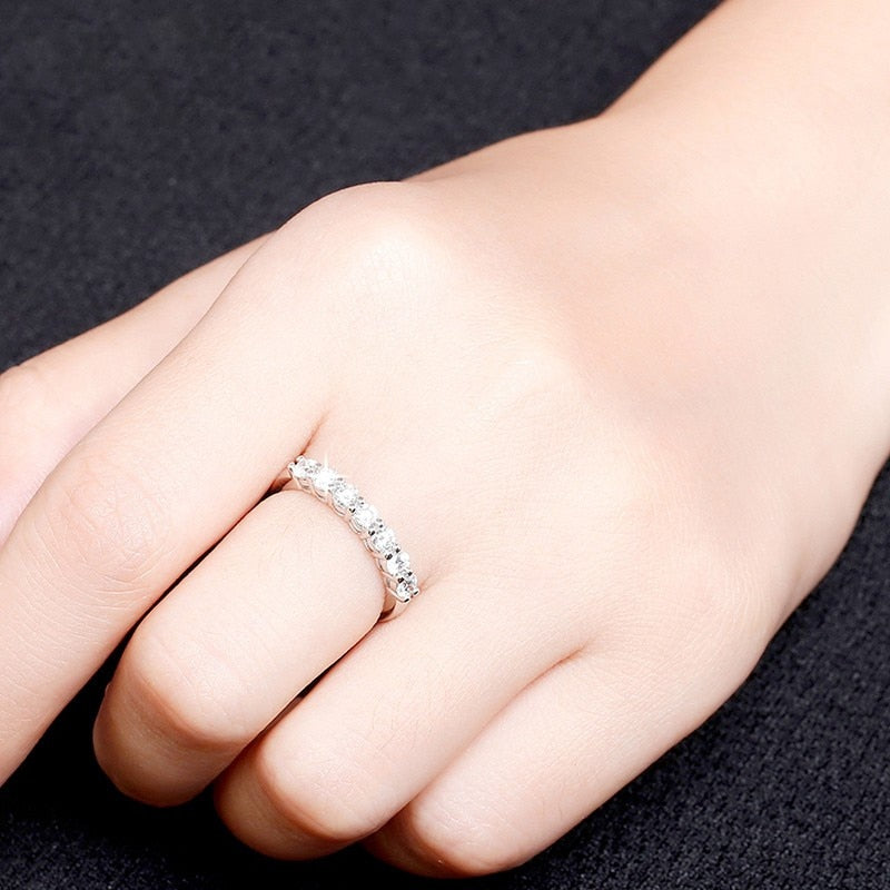 A hand wearing a silver 6 stone wedding ring.