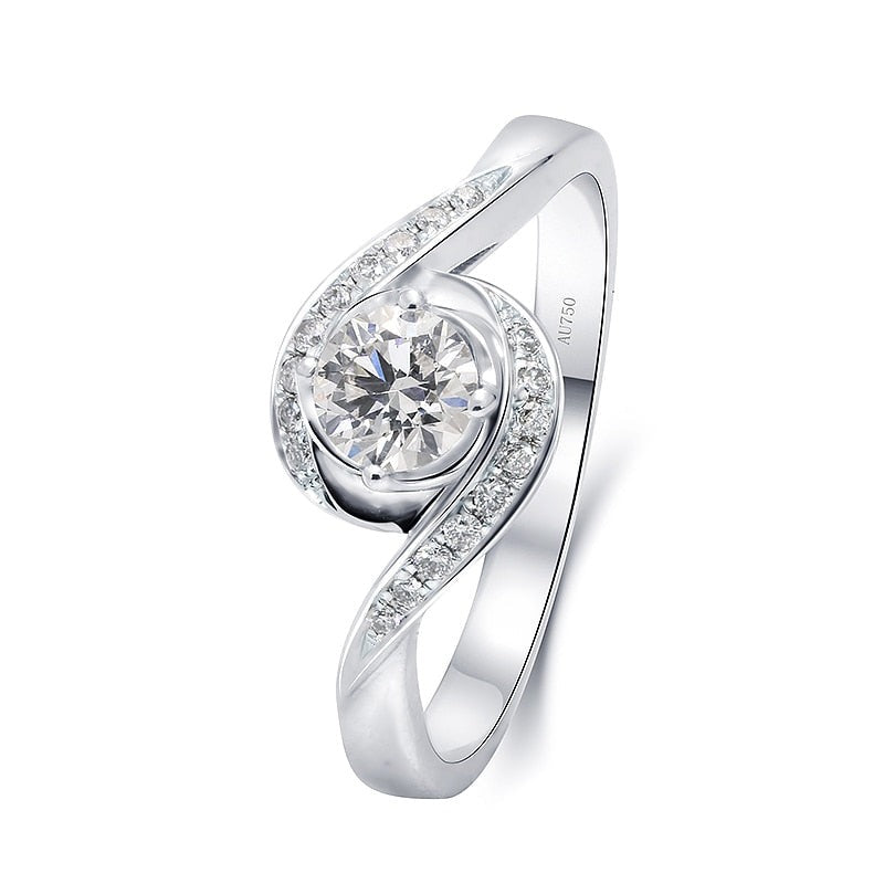 A silver round cut engagement ring set with a round moissanite on a pave bypass shank reminiscent of a wave.