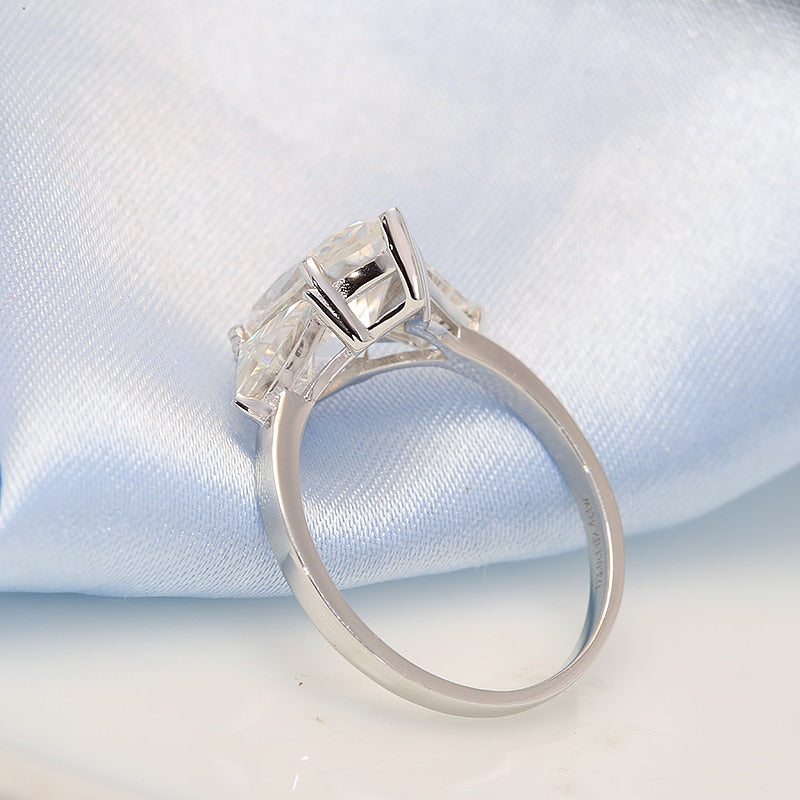 A silver 3 stone ring set with a 3CT marquise moissanite and with a 1.2CT trillion cut moissanite on each side.