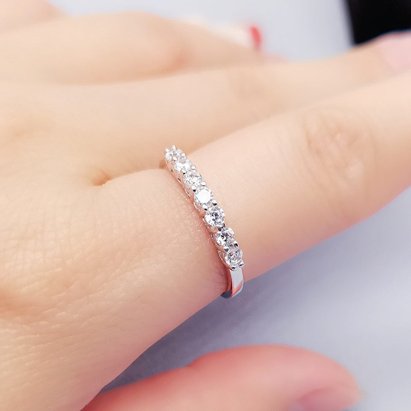 A hand wearing a silver ring set with seven 3x3mm moissanites.