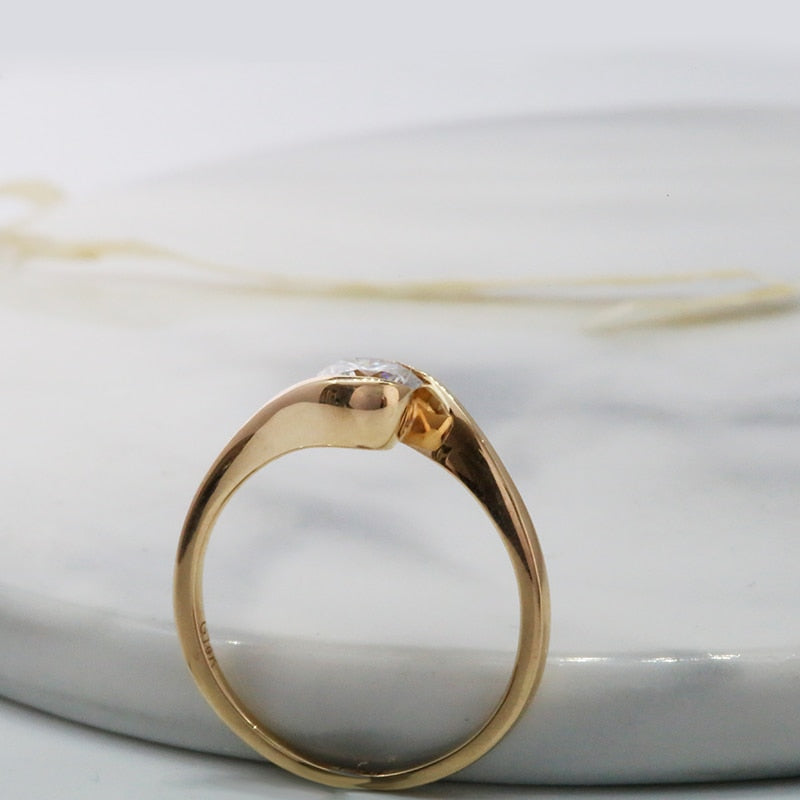 A gold round cut moissanite set in a bypass tension setting.