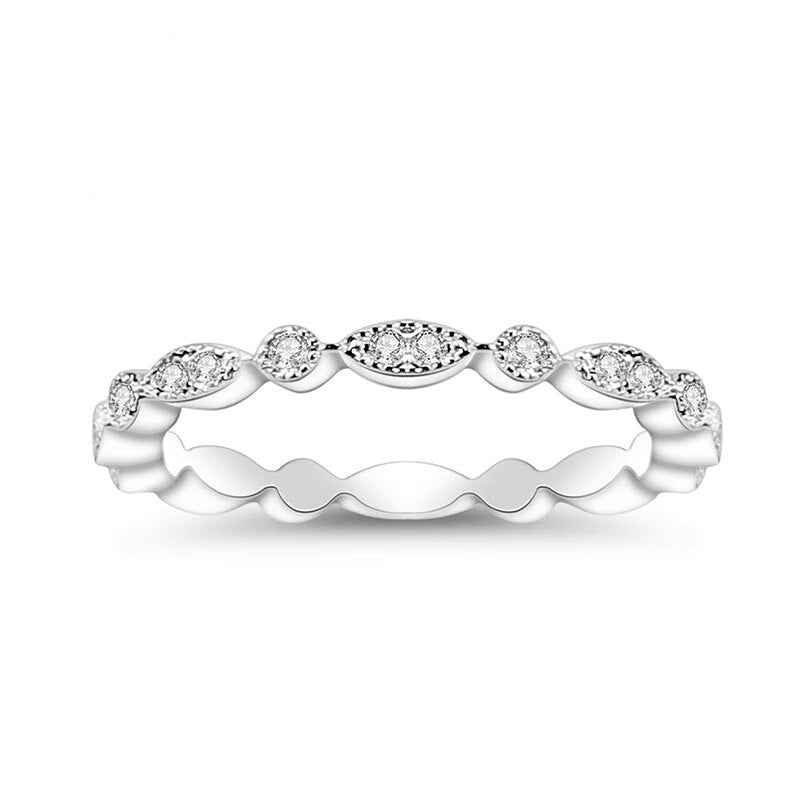 A silver scalloped art deco wedding band with small moissanites varying from 1 to 2 gems all the way around the eternity band.