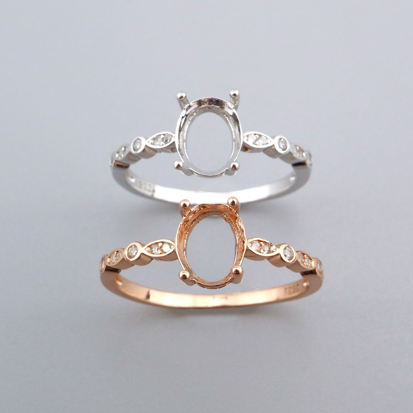 One silver and one rose gold oval art deco vintage settings with alternating bezel marquise and round gems on the sides.